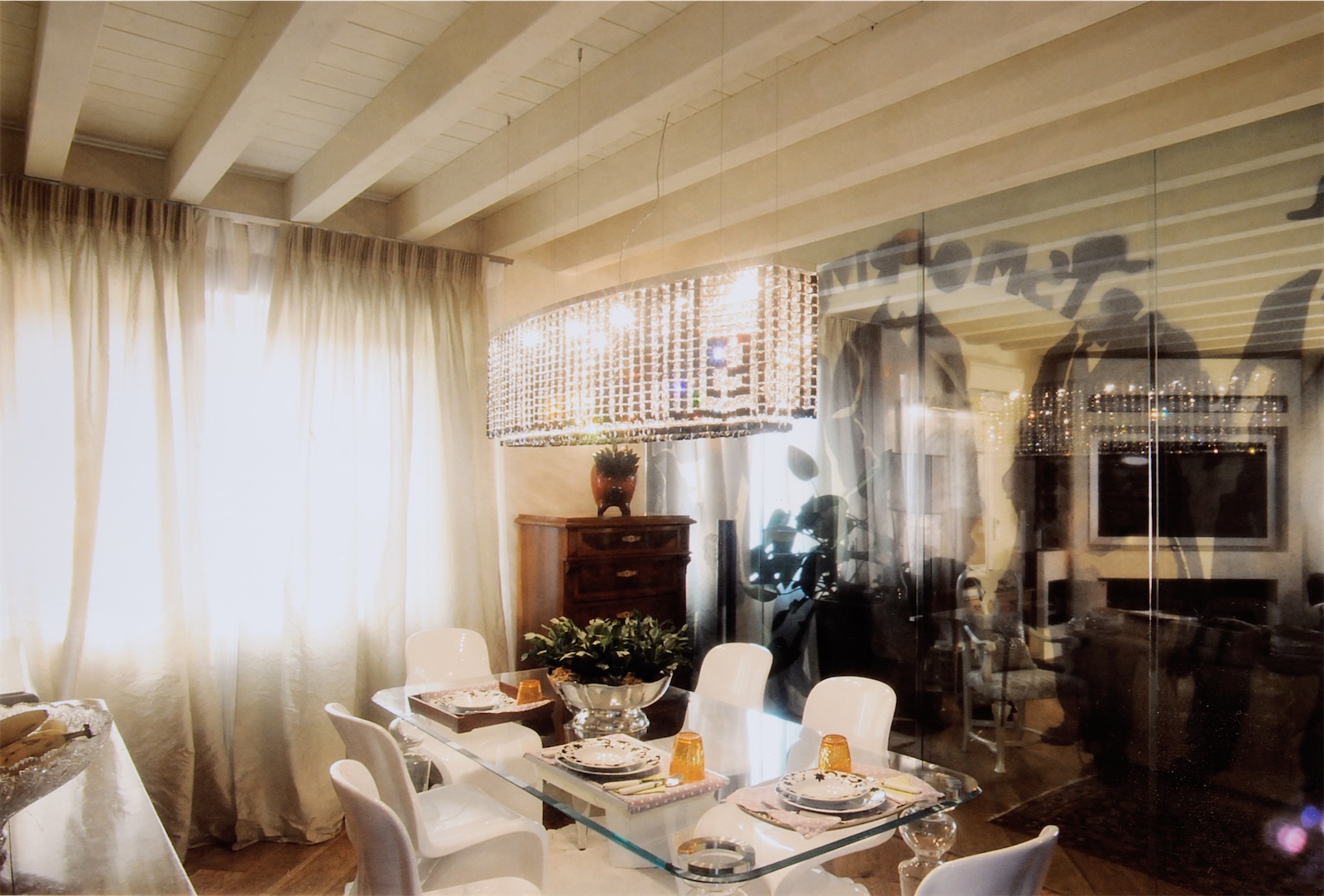 a living room with crystal dining table, light curtains and classy furniture in a Sardinian home