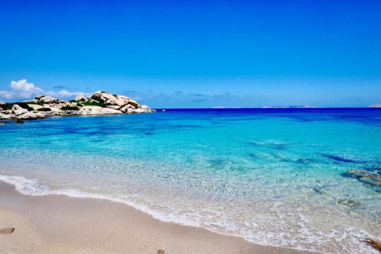 clean, clear water on a sardinian beach, with fine sand and a blue sky in the background